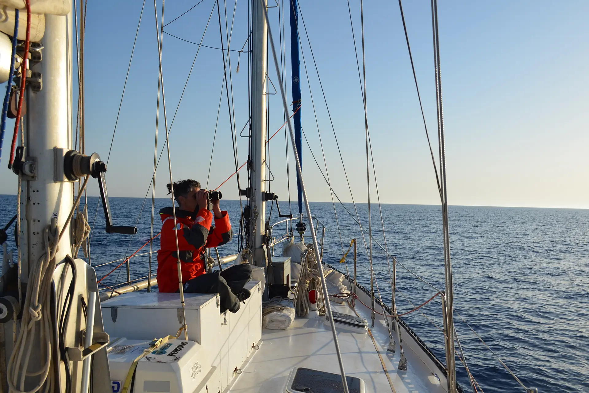 Crewmitglied auf der Imara mit Fernglas hält Wache.